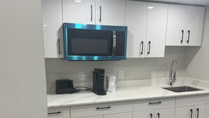 A modern kitchen with white cabinets, a stainless steel microwave, a coffee maker, and a sink. - New basement suite in a beautiful & nice location (Winnipeg)