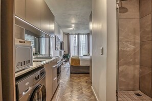Een moderne keuken met inbouwapparatuur, een eethoek en een slaapkamer met een groot raam.