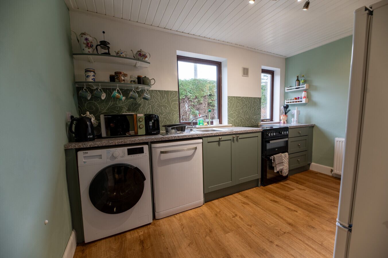 A compact kitchen with a washing machine, dishwasher, and a stove.