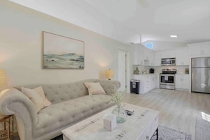 A modern living room with a beige sofa, a coffee table, and a painting on the wall.