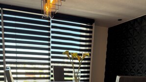Un comedor con una mesa dispuesta para dos personas, un florero con flores y una pared con diseño geométrico.