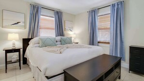 A bedroom with a bed, bedside tables, a dresser, and curtains. - Cottage 3 on Penn - Pool! (West Palm Beach)