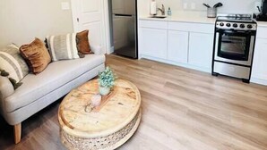 Una cocina moderna con armarios blancos, microondas integrado, refrigerador de acero inoxidable y estufa a gas.