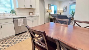 Een moderne keuken met witte kasten, een eettafel met stoelen en een kamerbreed tapijt.