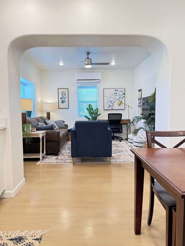 A living room with a sofa, a dark blue chair, a dining table, and a ceiling fan. - 2 Bed/1bath, two blocks from U of A! (Tucson)