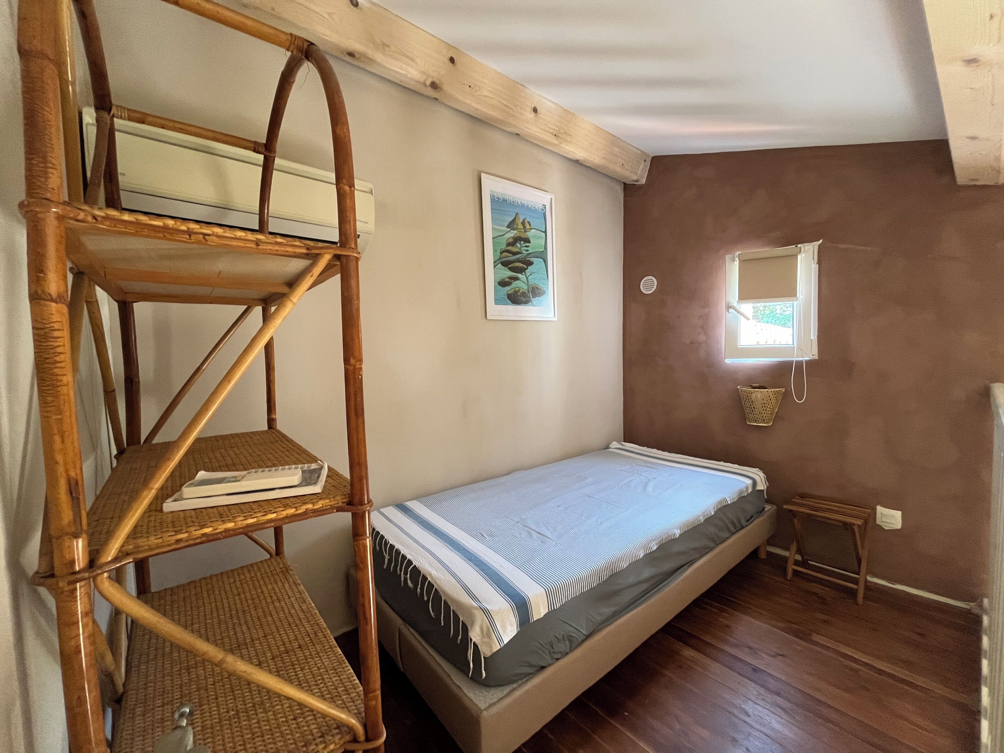 Ein kleiner, gemütlicher Raum mit Etagenbett, Holzregal, Tisch und Fenster.