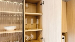 A wooden cabinet with shelves holding wine glasses and a bowl. - Premium studio apartment with pool, garage, and gym. (Joinville)