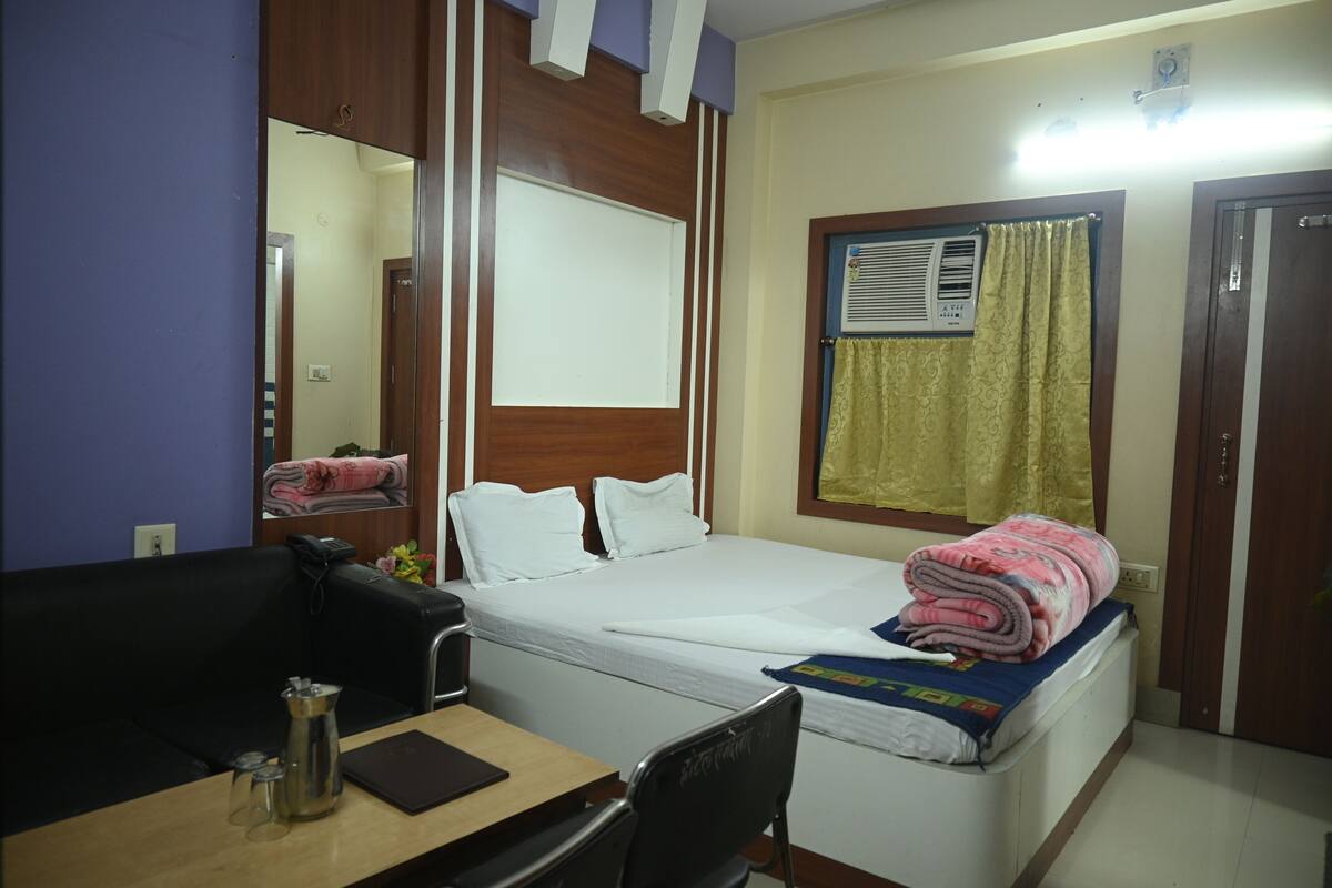 Une chambre d’hôtel comprenant un lit, un bureau avec une chaise, une machine à café et un miroir.