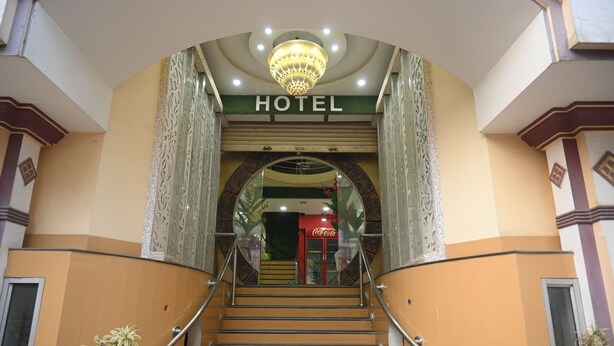 A hotel entrance with a staircase, a chandelier, and a Coca-Cola sign.