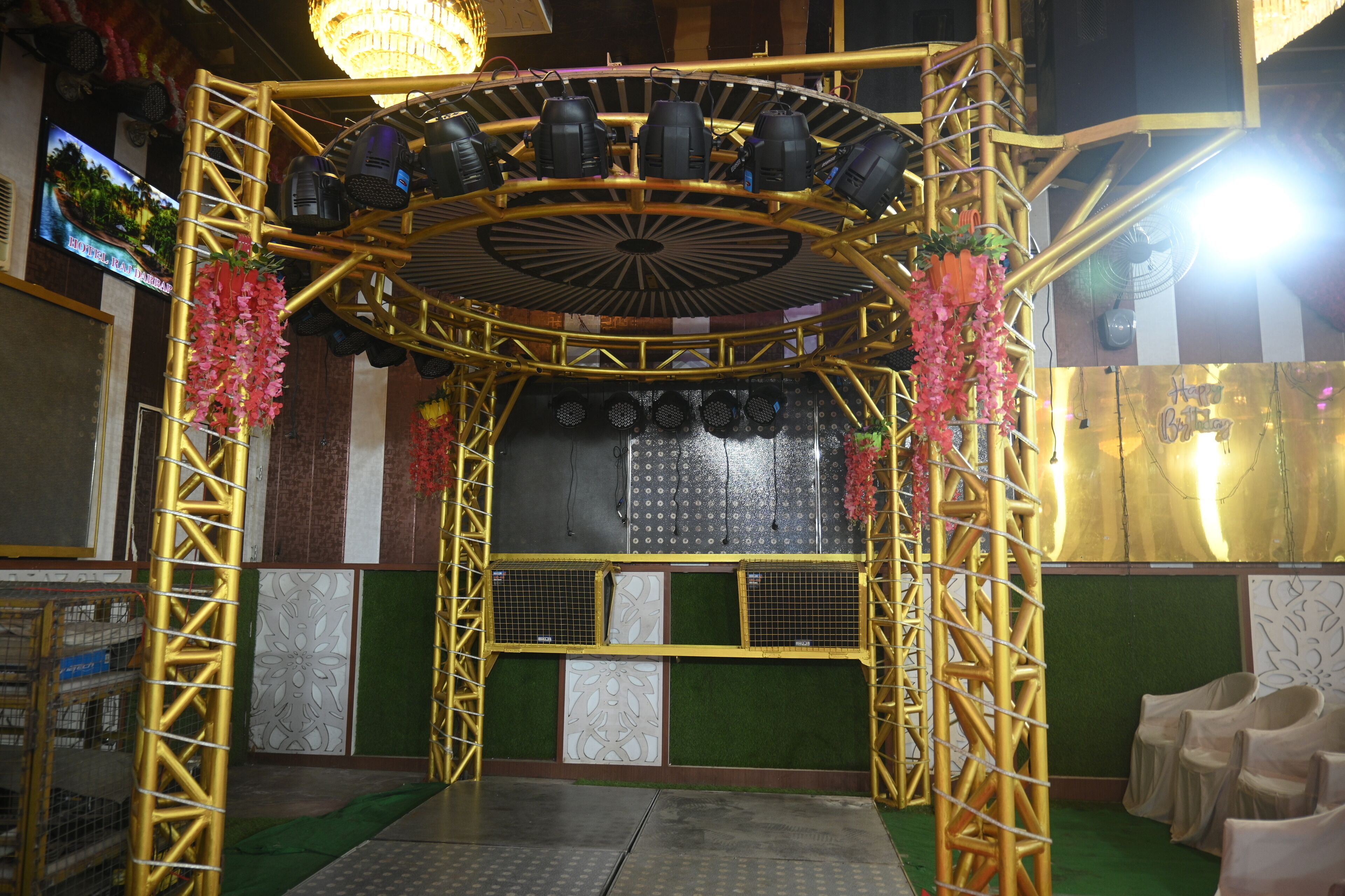 Un escenario con un marco dorado, varios micrófonos y flores decorativas.