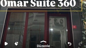 En bygning med flere balkoner, et skilt der siger 'Omar Suite 360', og et vindue med rødt gardin.