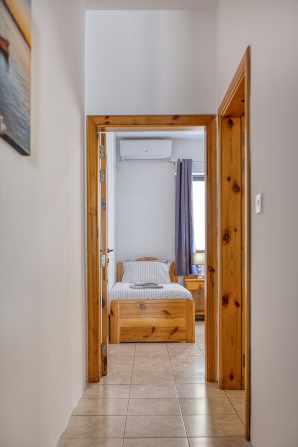 Un dormitorio con una cama de madera, una mesita de noche y un equipo de aire acondicionado.