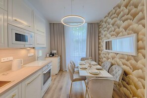 Una cocina moderna con muebles blancos, un microondas y un comedor con una mesa lista para cuatro personas.