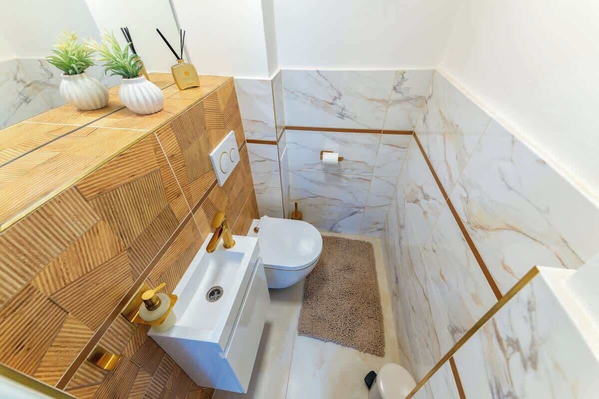 Un baño moderno con tocador de madera, lavamanos blanco y un inodoro.