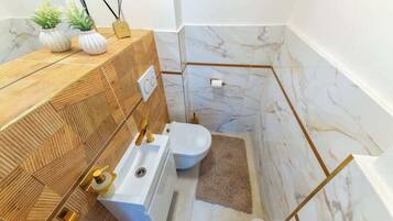 Un baño moderno con tocador de madera, lavamanos blanco y un inodoro.