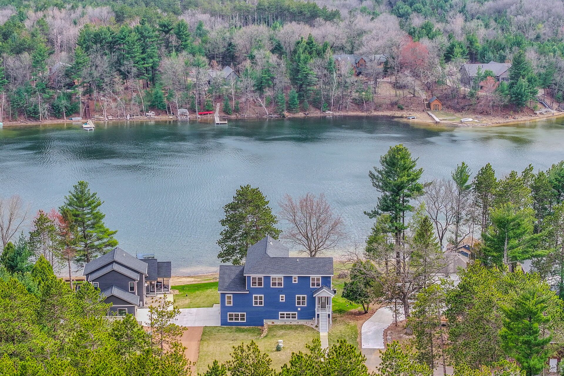 A residential area with houses near a lake, surrounded by trees.
