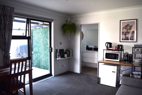 Una cocina compacta con refrigerador, microondas y cafetera sobre una mesa de madera.