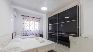 Une chambre à coucher comprenant un lit, une table de chevet, une fenêtre avec des rideaux et une porte-fenêtre coulissante donnant sur un balcon.
