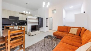 Un salon moderne comprenant un canapé, un téléviseur et un coin repas avec des chaises et une table.