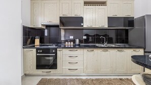Une cuisine moderne avec des meubles en bois clair, des plans de travail noirs, des appareils électroménagers en acier inoxydable et un four encastré.