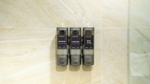 Three hand-poured bottles of shampoo, conditioner, and body wash on a marble wall. - Hotel Puerta Gala 2903 (Guadalajara)