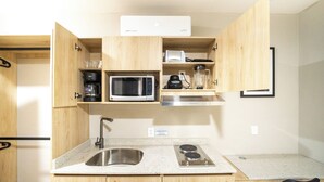 A compact kitchen with a microwave, coffee maker, blender, and a stainless steel sink. - Hotel Puerta Gala 2903 (Guadalajara)