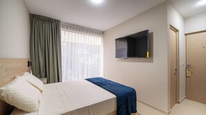 A bedroom with a bed, a TV mounted on the wall, a door, and a window with curtains. - Hotel Puerta Gala 2903 (Guadalajara)