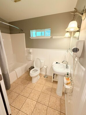 A bathroom with a bathtub, toilet, sink, and a window above the toilet. - ‘Spruce’ Riverfront Cabin near Olympic National Park (Beaver)
