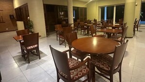 Un comedor amplio con varias mesas redondas y sillas, ventanas grandes y un diseño interior moderno.