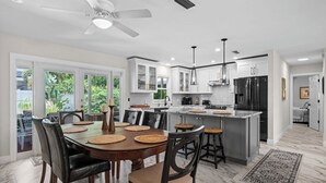 A modern kitchen with white cabinets, a black refrigerator, and a dining area with a round table and chairs. - Serene 3-bedroom house with AC in charming Venice (Venice)