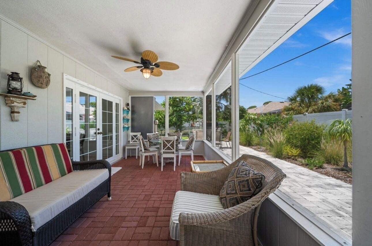 A covered patio with wicker furniture, a ceiling fan, and a view of the outdoors.