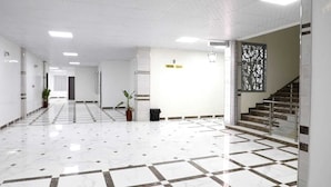 A spacious hallway with a tiled floor, a staircase, and a potted plant. - Hotel Tijiratt (Nouakchott)