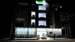 A multi-story hotel with a well-lit entrance and a visible signboard. - Hotel Tijiratt (Nouakchott)