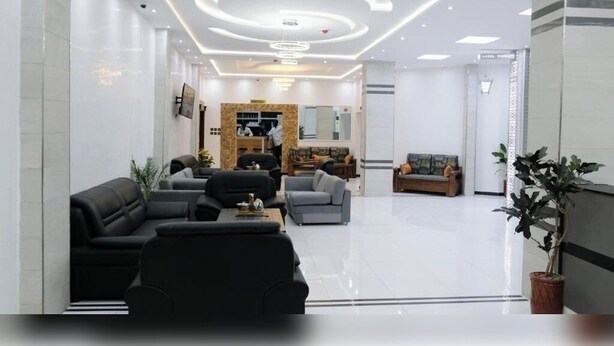 A modern hotel lobby with a reception desk, seating area, and a large mirror. - Hotel Tijiratt (Nouakchott)