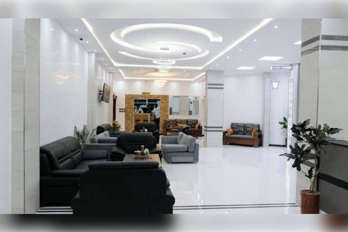 Un moderno vestíbulo de hotel con mostrador de recepción, zona de estar y un espejo grande.