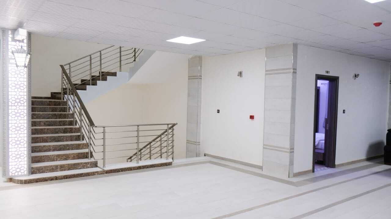 Un intérieur spacieux avec un escalier, une porte portant l’inscription « 101 », et un sol carrelé propre.