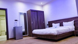 A bedroom with a large bed, a wardrobe, and a small cabinet. - Hotel Tijiratt (Nouakchott)