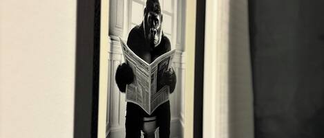 Fotografia in bianco e nero incorniciata che ritrae un gorilla intento a leggere un giornale.