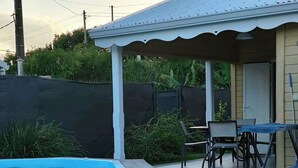 Een overdekt terras met een jacuzzi, buitenterras en een zwembad.