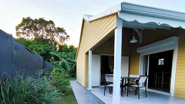 Een modern huis met een overdekt terras, een kleine tuin en een verharde oprit.