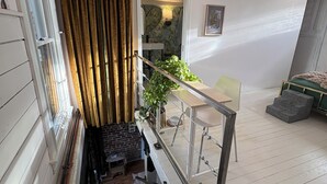 Eine Treppe mit Metallgeländer, ein Blumentopf, ein Essbereich mit Tisch und Stühlen sowie eine Wand mit einem gerahmten Bild.