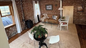 Ein Loft-Wohnraum mit freiliegenden Backsteinwänden, einem Kamin, einem Esstisch mit Stühlen und einem Sofa.