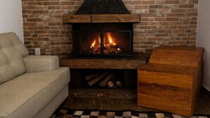 A cozy living room with a fireplace, a beige sofa, and a wooden coffee table.