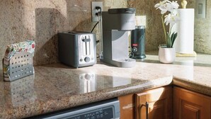 Una cocina con armarios de madera, encimera de granito, tostadora, cafetera y lavavajillas.