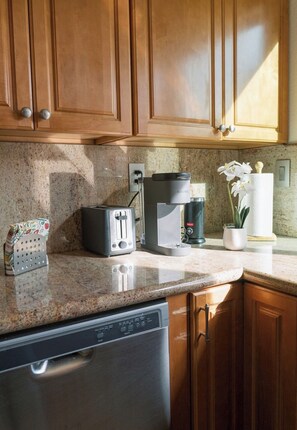 A kitchen with wooden cabinets, a granite countertop, a toaster, a coffee maker, and a dishwasher. - Superb 3-bedroom condo in the heart of Tempe. (Tempe)