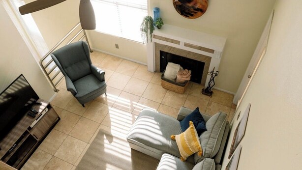 Una sala de estar con un sofá gris, un sillón azul, una chimenea y una escalera.