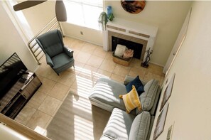 A living room with a grey sofa, a blue armchair, a fireplace, and a staircase. - Superb 3-bedroom condo in the heart of Tempe. (Tempe)