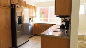 Una cocina moderna con armarios de madera, electrodomésticos de acero inoxidable y un amplio ventanal que proporciona luz natural.