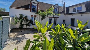 A two-story house with a sloped roof, a front porch, and a small garden area with plants. - Cozy House Near the Castle & Lakeside Leisure Area (Cepoy)