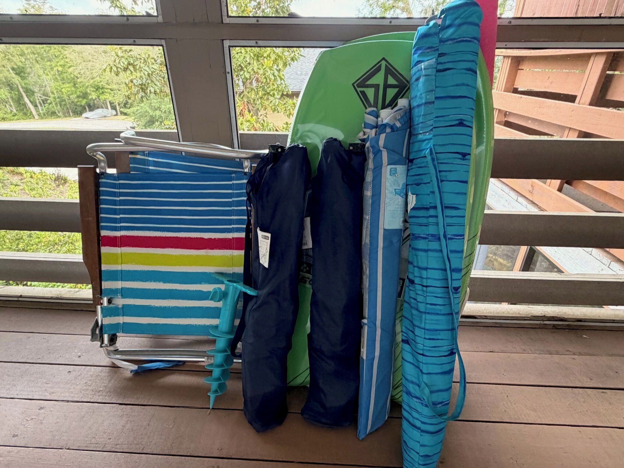 Un pontile in legno con ringhiera in metallo, un surfboard verde e un porta asciugamani a righe.